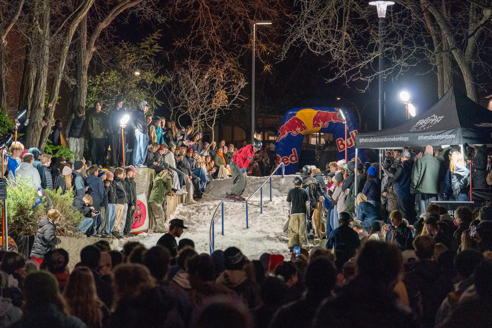 A rider sending the Old Library handrail at night while a packed campus crowd watches